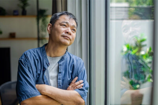 middle aged man day dreaming and looking through the window at home.